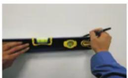 Person using a ruler to mark measurement points with green and yellow labels on a black surface