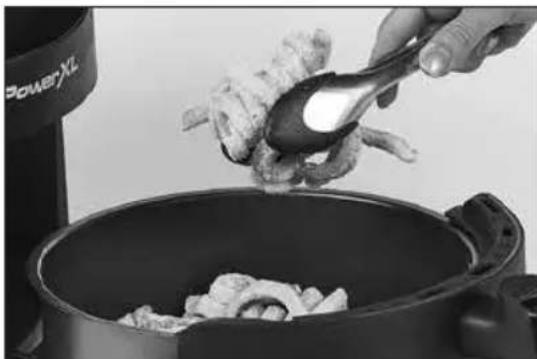 Close-up of a hand pouring raw meat from a ladle into a pan, with visible food and kitchen equipment in the background (no text or symbols)