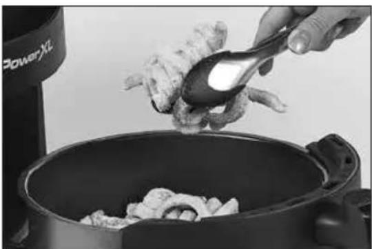 Close-up of a hand pouring raw chicken wings into a pan, with a power truck visible in the background (no text or symbols on main subject)