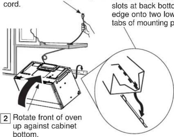 cord. 2 Rotate front of oven up against cabinet bottom. slots at back bottom edge onto two low tabs of mounting p