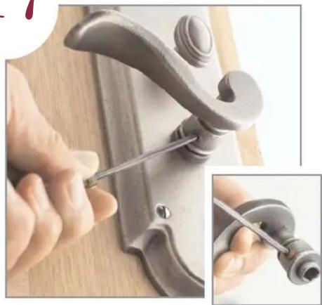 Close-up of hands using a tool to adjust or install a mechanical component, showing a curved handle and base (no text or symbols visible)
