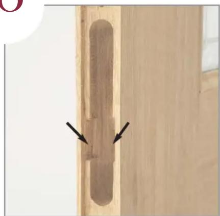 Close-up of a wooden door with a vertical scroll and two black arrows pointing to the edge (no text or symbols visible)