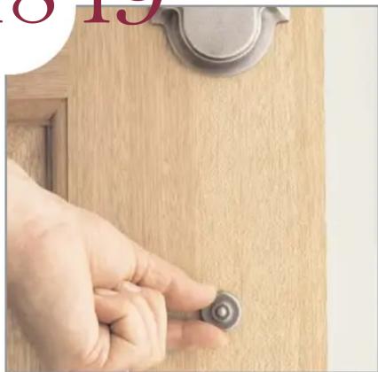 Close-up of a hand adjusting a small circular component on a wooden door (no text or symbols visible)
