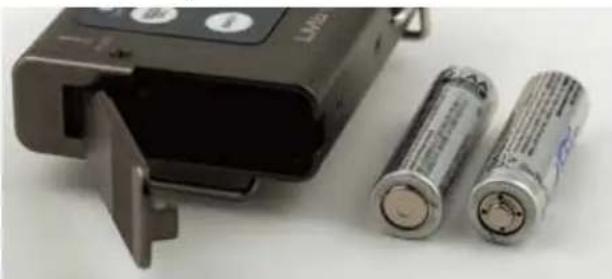 Two cylindrical batteries and a black LVM2 charging device, no visible text or symbols on the devices themselves.