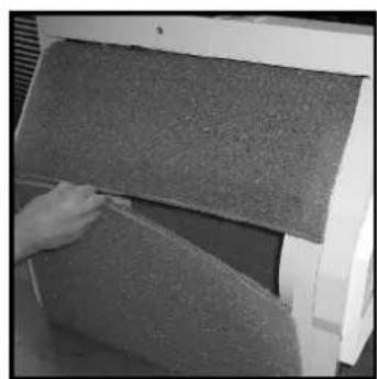 Close-up of a hand pressing down on a textured gray surface next to a white mechanical component (no visible text or symbols)