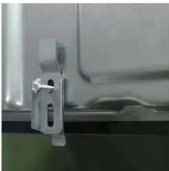 Close-up of a metallic mechanical bracket with mounting holes, mounted on a surface (no visible text or symbols)