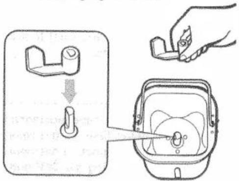 Diagram illustrating a hand holding a small object into a device, with a magnified view showing internal components.