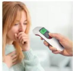 Woman holding a digital thermometer with a green screen, appearing to receive or observe something (no visible text or symbols)