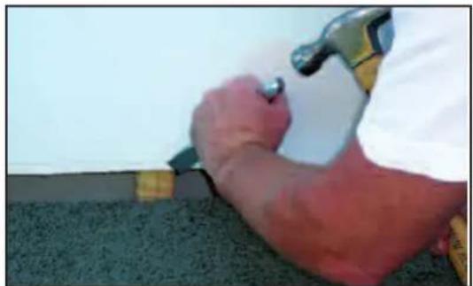 Close-up of a person using a hammer to work on a textured surface (no visible text or symbols)