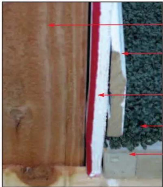 Close-up of a wooden wall joint with red and white painted lines, showing texture and material (no text or symbols visible)