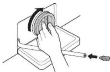 Hand holding a circular object with an arrow indicating rotation, next to a tool (no text or symbols).