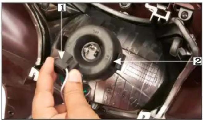 Close-up of a mechanical component with numbered parts and a hand pointing to a component, likely for assembly or repair documentation.