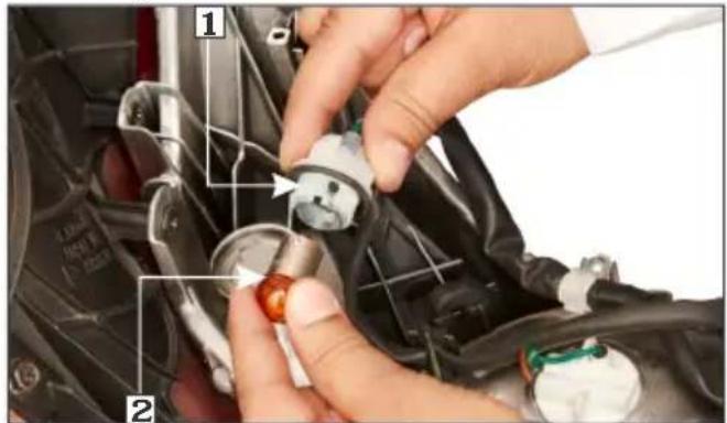 Close-up of hands installing a component with numbered parts, showing a red tool on a car engine component.