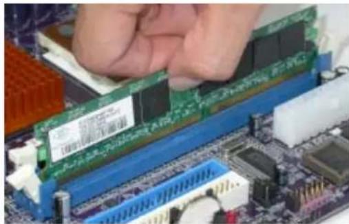 Close-up of a hand installing a green RAM module on a computer motherboard (no visible text or symbols)