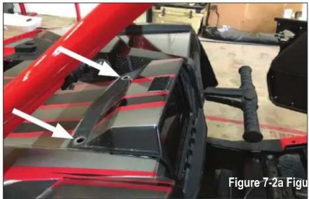 Close-up of a red and black vehicle chassis with white arrows pointing to specific components (no text or symbols visible)