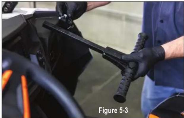 Person in blue shirt and black gloves handling a mechanical component, labeled 'Figure 5-3' (no other text or symbols visible)