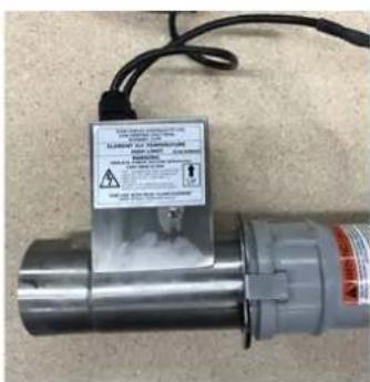 Close-up of a metallic industrial device with warning label and safety warnings visible