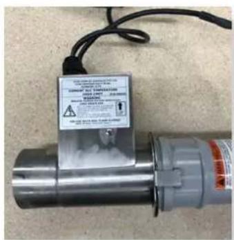 Close-up of a metallic industrial device with a warning label and cable, showing text about safety warnings and safety claims.