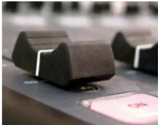 Close-up of a black industrial control switch with a pink button labeled 'NO' (no readable text or symbols beyond the button)
