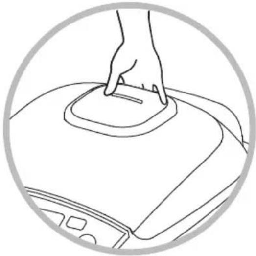 Line drawing of a hand pressing down on a circular mechanical component (no text or symbols)