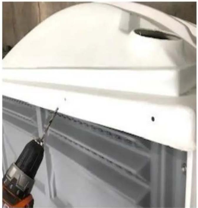 Close-up of a white industrial container with a drill bit and a tool inserted, no visible text or symbols.
