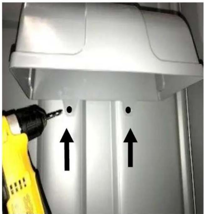 Close-up of a white industrial machine with two black arrows pointing up and down, being used by a yellow drill pen (no text or symbols visible)