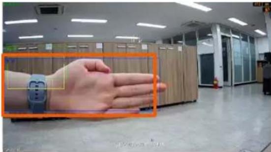 Photo of a hand wearing a smartwatch in an office with a magnified inset showing the wrist area and device placement.