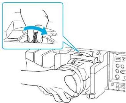 Diagram showing hands operating a mechanical device with a magnified inset highlighting the component's rotation.
