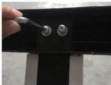 Close-up of a hand using a screwdriver to apply metal components on a black mechanical component (no visible text or symbols)