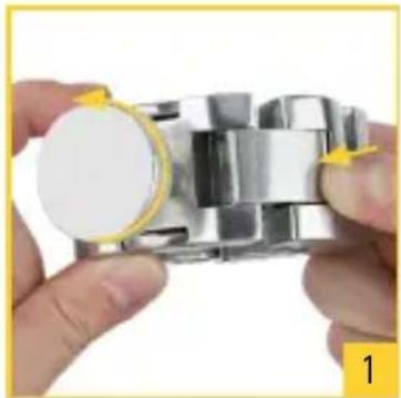 Close-up of hands assembling a metallic mechanical component with a yellow arrow indicating the part (no text or symbols visible)