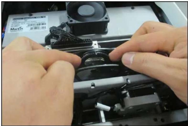 Close-up of hands installing or adjusting a mechanical component with a Martin fan and power supply (no visible text or symbols)
