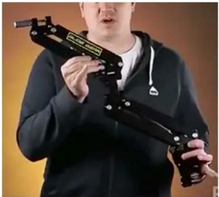 Person holding a black mechanical device with a label (no visible text or symbols on the device itself)
