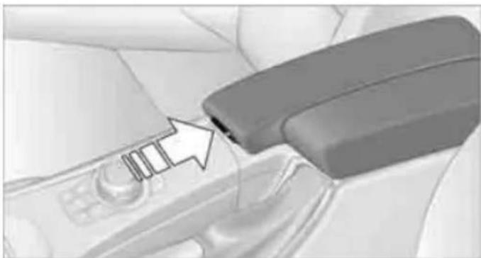 Close-up of a car headrest lever with a black arrow pointing to the control panel (no text or symbols visible)