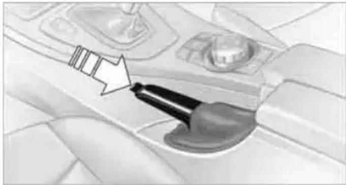 Interior view of a car dashboard with a hand tool inserted, showing no visible text or symbols.