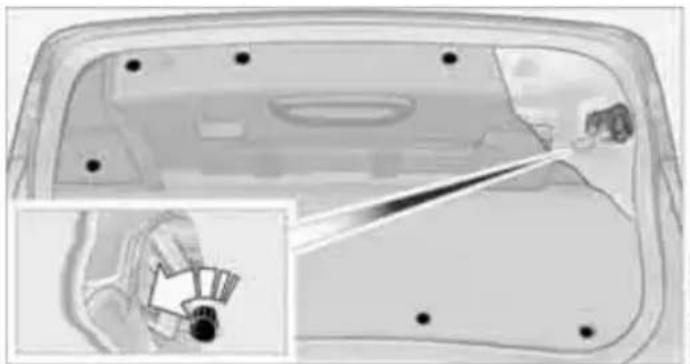 Interior view of a car door frame with a hand holding a small object, showing no text or symbols.