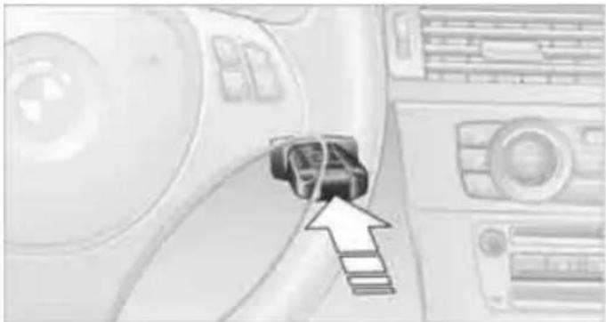 Close-up of a car interior with a black connector and directional arrow pointing to the component (no visible text or symbols)