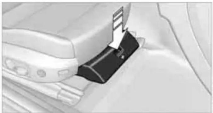 Close-up of a car interior showing a black plastic clip inserted into a white plastic sheet (no text or symbols visible)