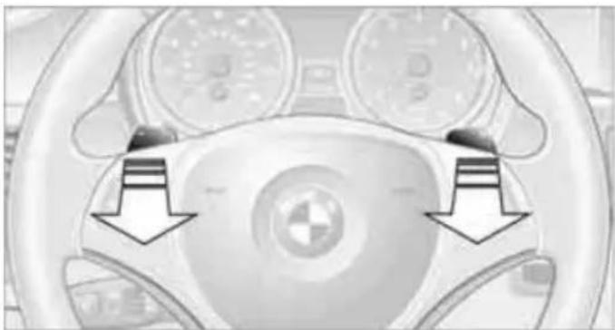 Close-up of a car's steering wheel with two arrows pointing to the dashboard (no text or symbols visible)