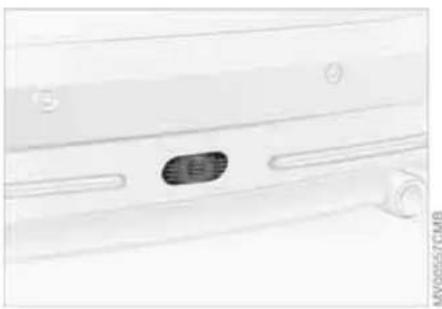 Close-up of a white car door panel with a dark oval object on the side (no visible text or symbols)
