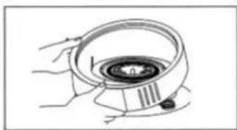 Illustration of hands holding a circular device with a central knob and a pointer (no text or symbols)
