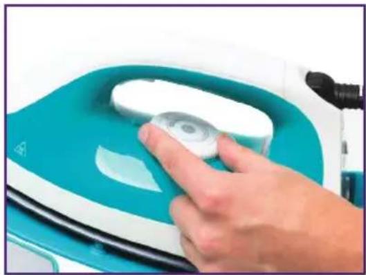 Close-up of a hand pressing a circular component on a teal and white iron cutting machine (no text or symbols visible)