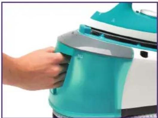 Close-up of a hand pressing down on a teal-colored iron or steam iron (no visible text or symbols)