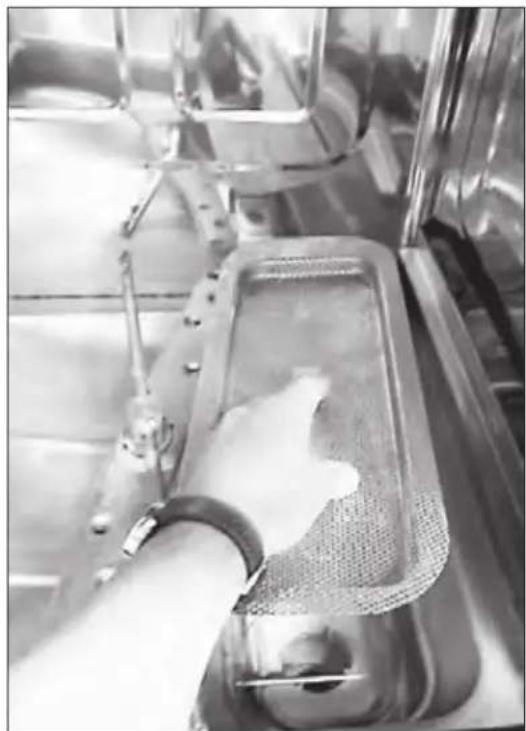 Close-up of a hand pouring white powder into a metal tray inside a stainless steel mixing tank (no visible text or symbols)