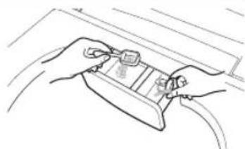 Line drawing of two hands inserting a small electronic component into a device (no text or symbols)