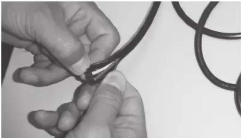 Close-up of hands tying a knot around a black cable (no text or symbols visible)