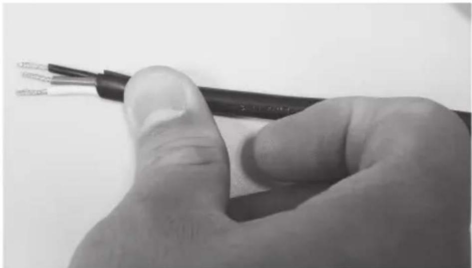 Close-up of a hand holding a black cable with exposed wires, no text or symbols visible