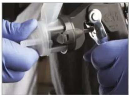 Close-up of gloved hands performing a medical procedure with a metallic device (no visible text or symbols)