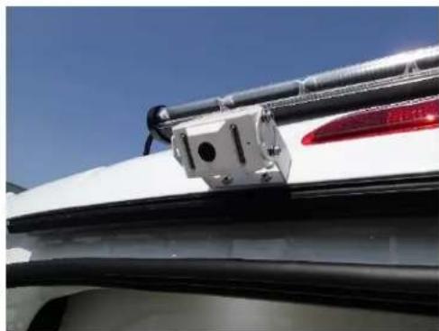 Close-up of a white car's front bumper with black railings and a red LED light, against a clear blue sky (no text or symbols visible)