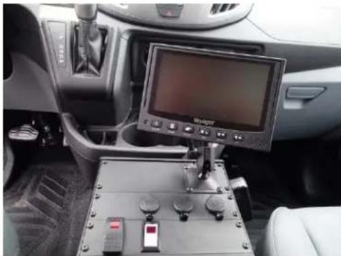 Interior view of a vehicle cockpit with a mounted control panel and display screen (no visible text or symbols)