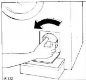 Hand placing a small object into a box with an arrow indicating rotation (no text or symbols)
